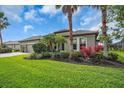 Beautifully landscaped front yard with vibrant plants, palm trees, and manicured lawn at 988 145Th Street Ne Cir, Bradenton, FL 34212