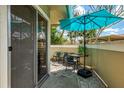 Cozy outdoor patio featuring stylish stone flooring, seating for four, and a vibrant blue umbrella providing ample shade at 3008 Sail Pointe Cir # 2C, Venice, FL 34293