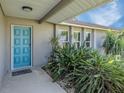 Inviting front entrance features a stylish blue door and lush tropical landscaping at 1234 Pinebrook Way, Venice, FL 34285