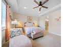 Serene bedroom featuring a ceiling fan, tray ceiling, sitting area, and ensuite bathroom at 13897 Umbria St, Venice, FL 34293