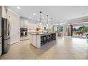 Bright kitchen with granite island, barstool seating, tiled floors, modern appliances, and access to an outdoor patio at 13897 Umbria St, Venice, FL 34293