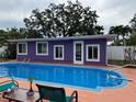 Outdoor swimming pool with a vibrant purple house backdrop and neatly landscaped surroundings at 1460 Everest Rd, Venice, FL 34293