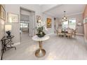 Elegant foyer featuring a marble-topped table with a floral display, light wood floors, and a view into the dining room at 208 Corelli Dr, Nokomis, FL 34275