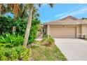Beige home featuring a one-car garage, tile roof and tropical landscaping in a well-maintained neighborhood at 335 Auburn Woods Cir, Venice, FL 34292