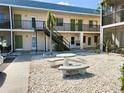 Exterior courtyard view with a stone picnic table and chairs, and condo building with green doors in background at 616 Guild Dr # 2, Venice, FL 34285