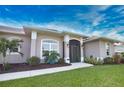 Close up on the front entrance of the home with a screened door, arched windows, and manicured landscaping at 863 Southland Rd, Venice, FL 34293
