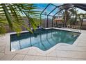 A screened in pool area with a waterfall feature and an outdoor dining set, surrounded by lush landscaping at 863 Southland Rd, Venice, FL 34293