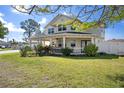 Charming two-story home with a covered front porch, well-manicured lawn, and lush landscaping at 915 Citrus Rd, Venice, FL 34293