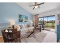 Bright living room with blue walls, white couch, and sliding doors to a balcony overlooking lush greenery at 925 Capri Isles Blvd # 4, Venice, FL 34292