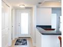 Bright hallway leading to a door with a frosted window and the kitchen at 1100 Tarpon Center Dr # 102B, Venice, FL 34285