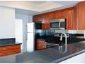 Kitchen with wood cabinets, stainless steel appliances, and black countertops at 1100 Tarpon Center Dr # 102B, Venice, FL 34285