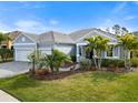 Charming home featuring a two-car garage, lush landscaping, and well-manicured lawn at 12456 Destin Loop, Venice, FL 34293
