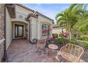 Inviting front porch with brick pavers and seating area surrounded by tropical landscaping at 13215 Amerigo Ln, Venice, FL 34293