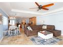 Open-concept living room featuring a large sectional sofa, ceiling fan, and travertine tile flooring at 1440 Overbrook Rd, Englewood, FL 34223