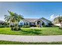 Well-maintained single-story home with a manicured lawn, tropical palm trees, and colorful flowerbeds at 1611 Valley Dr, Venice, FL 34292