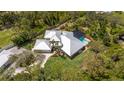 Expansive aerial view showcases the home's metal roof, pool, and lush greenery in a private, wooded setting at 1657 Bayshore Dr, Englewood, FL 34223