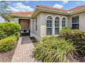 Welcoming front entrance featuring arched windows, a decorative glass block, and vibrant landscaping at 177 Treviso Ct, North Venice, FL 34275