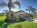 Inviting single-story home with vibrant landscaping, palm trees, and a brick driveway, perfect for curb appeal at 19124 Mangieri St, Venice, FL 34293