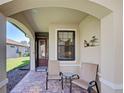 Inviting front porch with brick flooring, seating, and a decorative metal sculpture, creating a welcoming entrance at 19124 Mangieri St, Venice, FL 34293