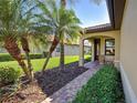 Cozy covered porch with brick flooring, seating area, and lush landscaping, offering a relaxing outdoor space at 19124 Mangieri St, Venice, FL 34293