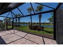 Screened lanai with brick flooring overlooks a serene lake view surrounded by lush landscaping at 19297 Serafina, Venice, FL 34293