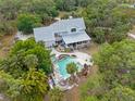 Aerial view of a luxurious pool and outdoor entertaining area surrounded by mature trees and lush greenery at 202 Laurel Oaks Rd, Nokomis, FL 34275