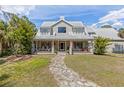 Charming home with a wide front porch, rocking chairs, stone walkway, and a well-manicured lawn at 202 Laurel Oaks Rd, Nokomis, FL 34275