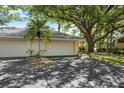 Spacious driveway leading to a two-car garage, surrounded by mature landscaping and trees at 226 Southampton Ln # 257, Venice, FL 34293