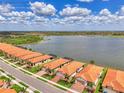 Wide aerial view showing the community, homes with red tile roofs, and stunning lake at 24128 Spartina Dr, Venice, FL 34293