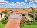 Charming single-story home featuring lush landscaping, a brick driveway, and an attached two car garage at 24128 Spartina Dr, Venice, FL 34293