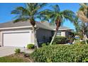 Inviting home exterior with a two-car garage, complemented by vibrant landscaping and mature palm trees at 3419 Lakewood Blvd, North Port, FL 34287