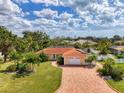 Stunning single-story home boasts a red tile roof, brick driveway, and lush landscaping at 403 Picasso Dr, Nokomis, FL 34275