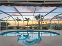 A screened-in pool features a lovely water feature and sunset views overlooking the water at 5035 Collingswood Blvd, Port Charlotte, FL 33948