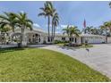 Sprawling single-story home boasts verdant lawn, paved driveway, and palm-lined landscaping at 701 Laguna Dr, Venice, FL 34285