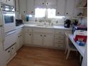 Bright kitchen featuring white cabinets, laminate wood flooring and a double basin sink at 722 Carefree, Venice, FL 34285