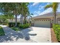 Beautiful home featuring a two-car garage and well-maintained landscaping, complemented by mature trees and manicured shrubs at 9413 Carnaby Dr, Venice, FL 34293