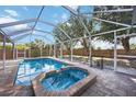 Sparkling screened pool and spa offer a refreshing oasis with ample patio space and serene backyard views at 10047 Greetings St, Port Charlotte, FL 33981
