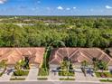 An aerial view of a villa with a tile roof, a paver driveway, a well-manicured lawn, and lush landscaping at 11096 Campazzo Dr, Venice, FL 34292
