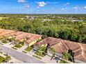 An aerial view of a villa with a tile roof, a paver driveway, a well-manicured lawn, and lush landscaping at 11096 Campazzo Dr, Venice, FL 34292