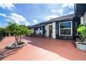 Stylish home featuring an outdoor lounge area, mature landscaping, and a bright red driveway at 23 Tiffany St, Englewood, FL 34223