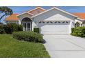 Charming home featuring a well-maintained lawn, beautiful landscaping, and a two-car garage with stylish detailing at 4843 Orange Tree Pl, Venice, FL 34293