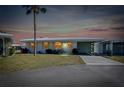 Charming home exterior with yellow shutters and tropical landscaping at dusk at 595 Circlewood Dr # Y4, Venice, FL 34293