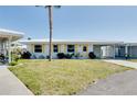Bright single-story home featuring white exterior, yellow shutters, front lawn, and attached carport at 595 Circlewood Dr # Y4, Venice, FL 34293