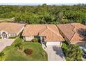 A sunny aerial shot of a single-story home with a terracotta roof, lush landscaping, and a two-car garage at 8300 Parkside Dr, Englewood, FL 34224