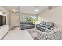 Bright living room with white tile flooring, neutral walls, and comfortable gray leather seating at 8300 Parkside Dr, Englewood, FL 34224