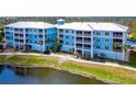 Scenic view of blue condo buildings with white trim, situated by a tranquil pond and lush greenery at 8405 Placida Rd # 206, Placida, FL 33946