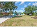 Two-story turquoise home with a well-manicured lawn, mature landscaping, and a spacious concrete driveway at 938 The Rialto, Venice, FL 34285