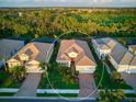 An aerial view captures a well-maintained home with verdant landscaping, a red tile roof, and a paver driveway at 27336 Driver Ln, Englewood, FL 34223