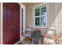 Charming front porch with a red door, shuttered window and outdoor seating at 11026 Barnsley Dr, Venice, FL 34293