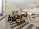 A open concept living room with a coffee table, green sofa and eat-in kitchen with bar seating at 13166 Huerta St, Venice, FL 34293